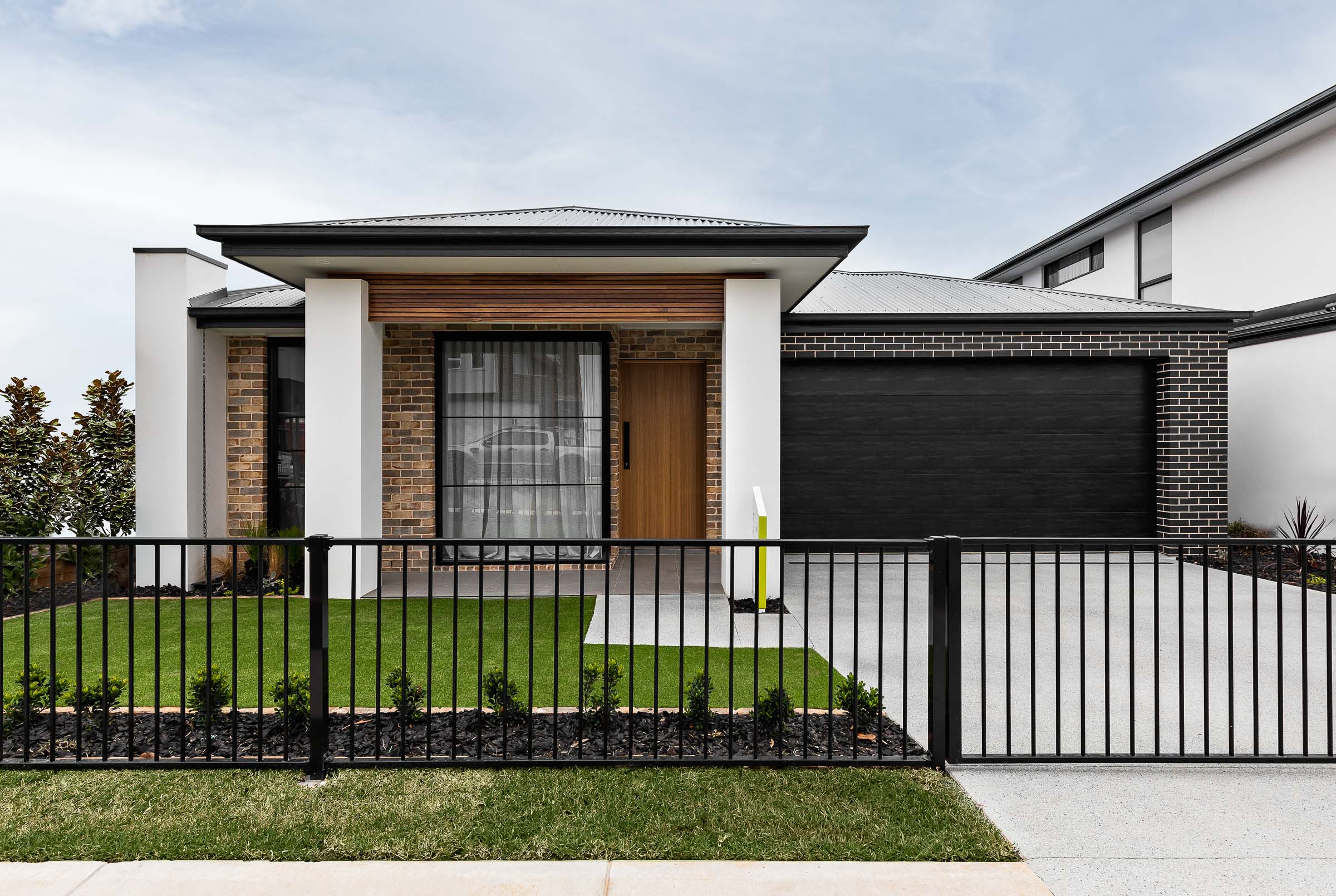 Modern single-storey home with wooden accents and black garage, designed by King Homes NSW